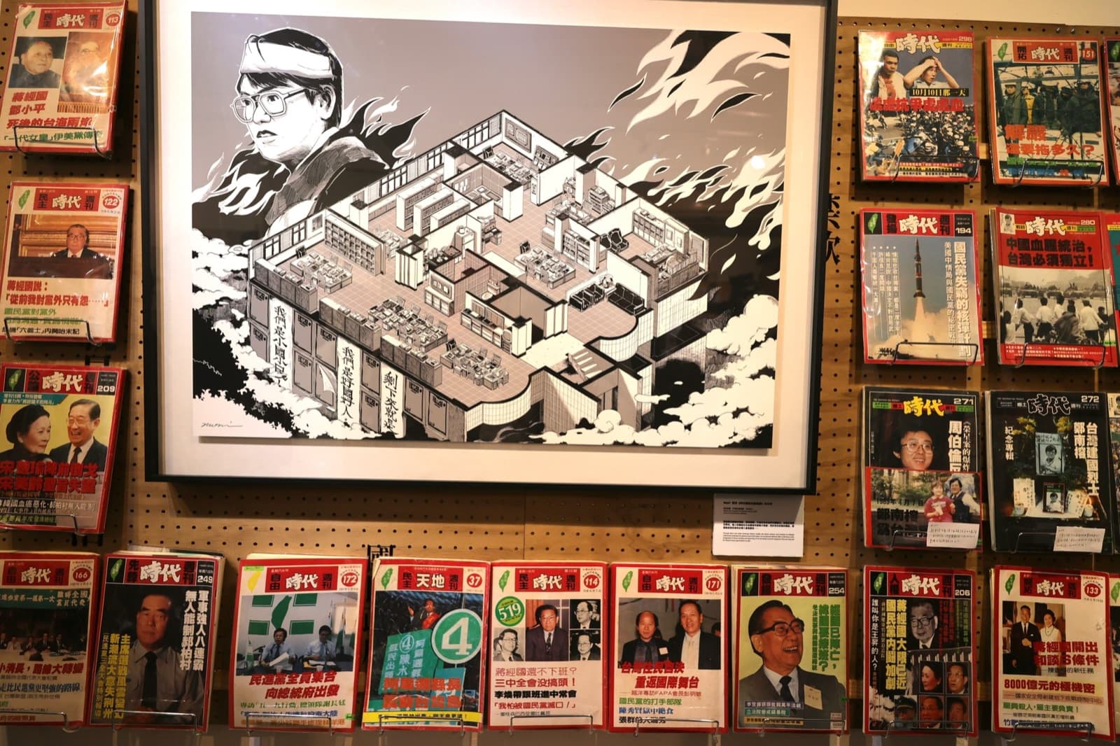 展出中的《自由時代》系列週刊,中間是描繪鄭南榕與雜誌社的畫作,二〇二三年攝。雜誌每被查禁一期,就換一張執照繼續出,封面上的刊名因此常常不一樣。