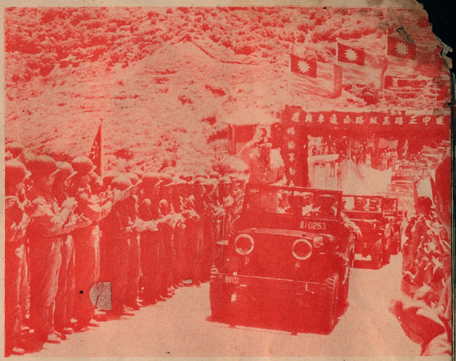 The opening ceremony for the paved surface of Zhongzheng Road on Nangan, 11 May 1962. The ranks lining the road are soldiers in steel helmets, and the motorcade passes beneath an arch hung with national flags.