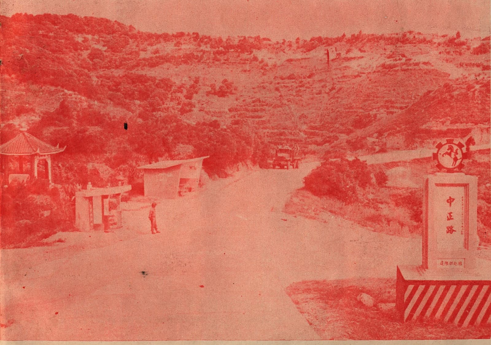 Zhongzheng Road on Nangan, around 1962. A road-name marker stands at the junction on a base painted in red and white diagonal stripes, and a military truck is coming down the slope in the distance. The photograph appears in Matsu Scenery, compiled by the Matsu Garrison Command.