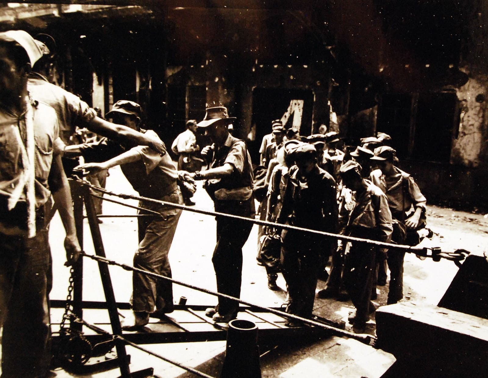 British and Australian prisoners of war freed on Formosa go aboard the US Navy destroyer escort Thomas E. Gary, 1945. The original caption adds a single line: the men are weak from malnutrition and must be helped on board.