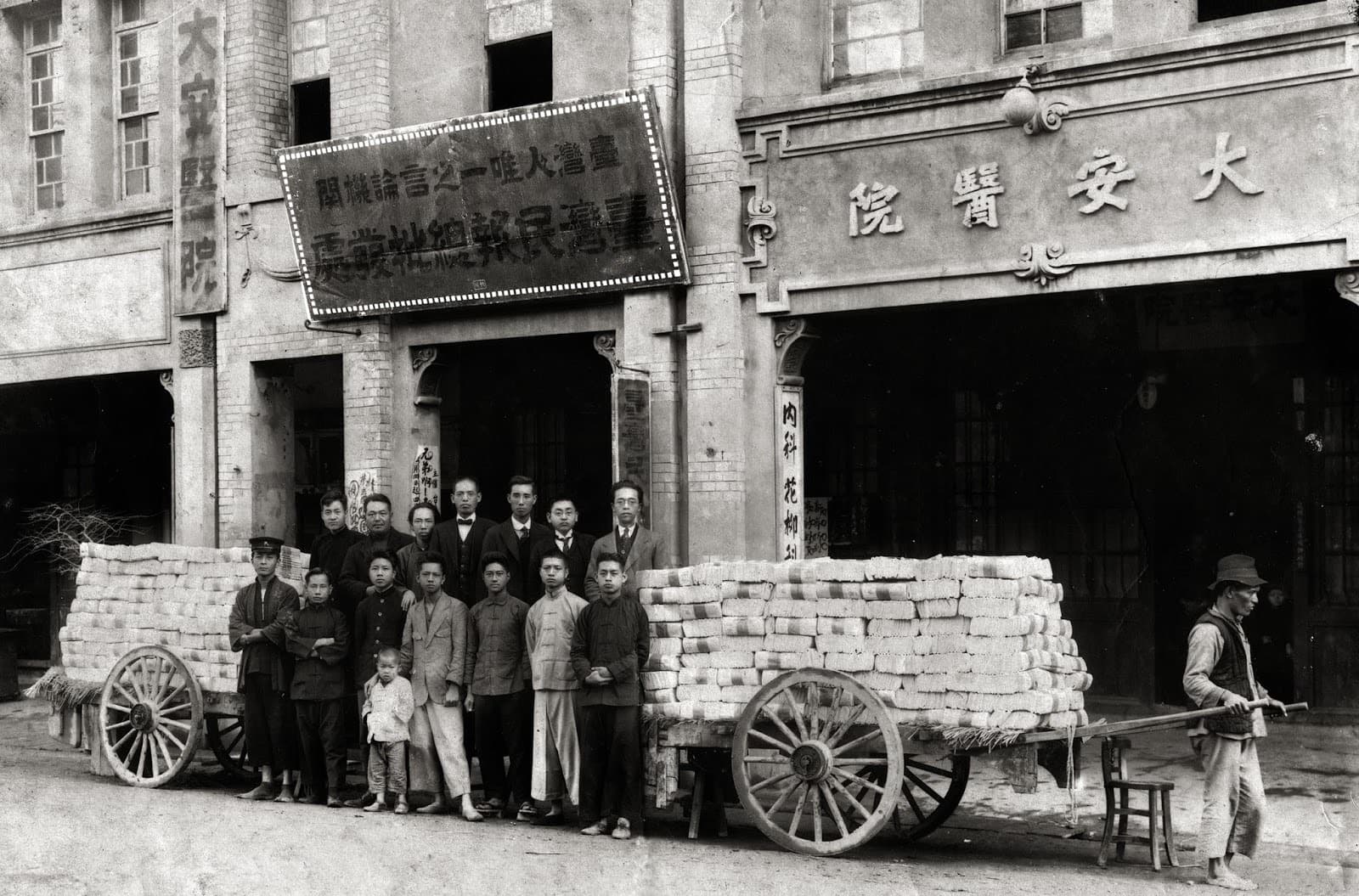 Staff of *The Taiwan Minpao* outside the paper's office, 1925. It was printed in Tokyo and shipped back, because a press on the island would not have cleared the censor. The bundles on the carts are copies waiting to go out.